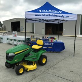 Pictured is the Talbert Building Supply tent and a John Deer Lawnmower. The mower was the Grand Prize at our Annual Vinyl Show in 2019.